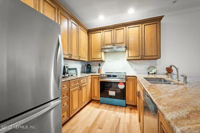 a kitchen with stainless steel appliances granite countertop a stove a sink dishwasher and a refrigerator