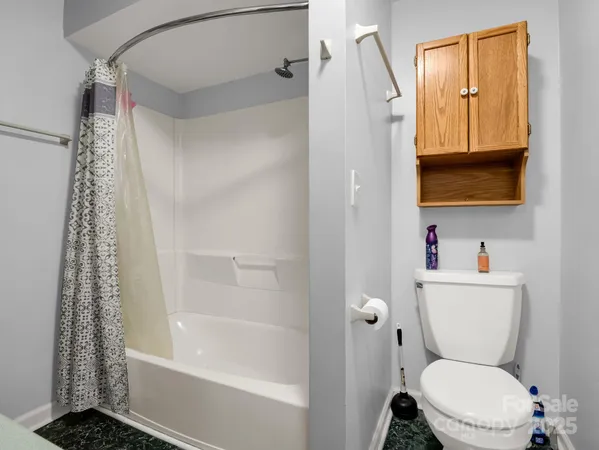 an empty room with chandelier fan and windows