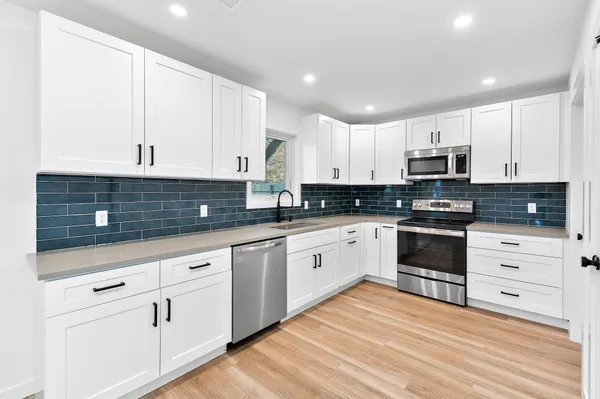 a kitchen with granite countertop white cabinets and stainless steel appliances