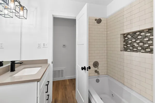 a bathroom with a tub sink and mirror