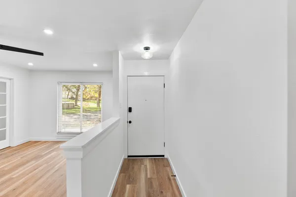 a view of hallway with window and wooden floor