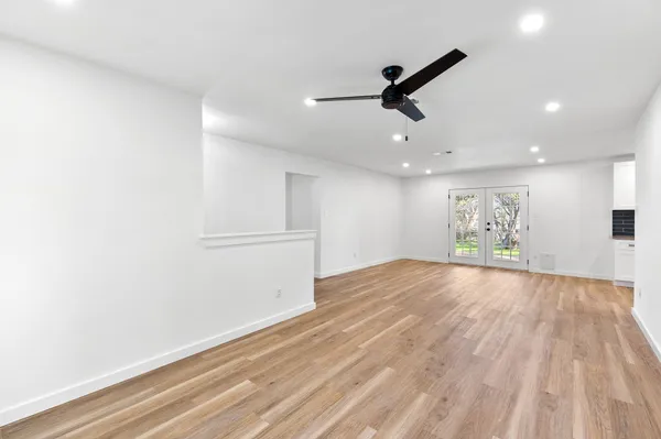 a view of empty room with wooden floor and ceiling fan