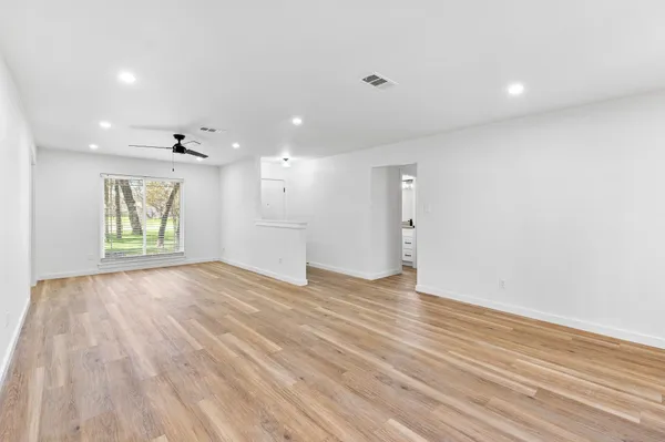an empty room with wooden floor and windows