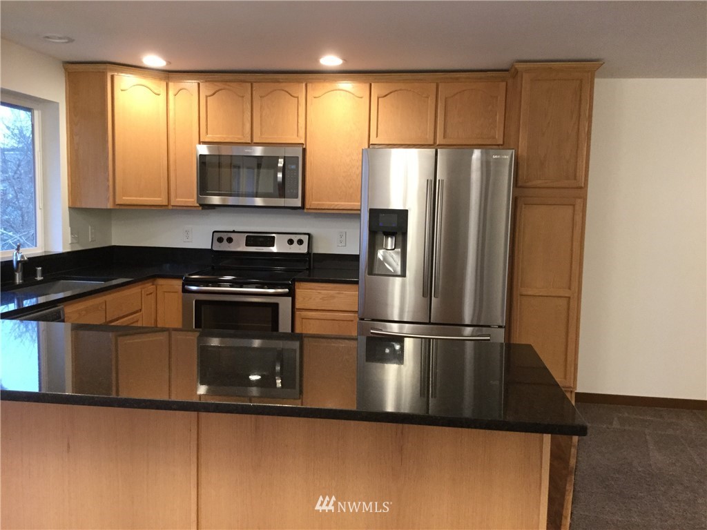4606 Wood Place Everett, WA 98203 - Photo 4 of 37 a kitchen with granite countertop a refrigerator and a stove top oven