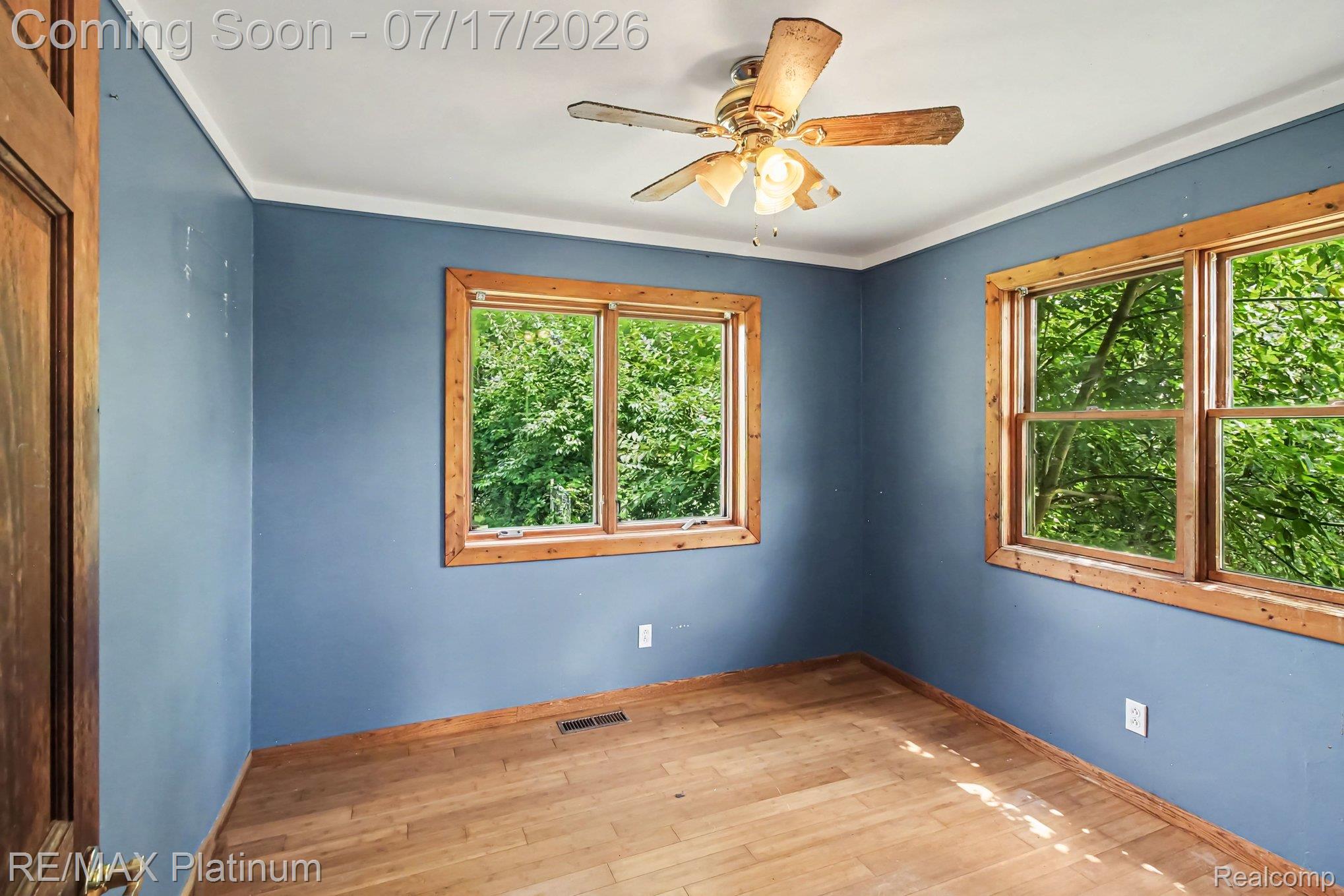4205 Musson Road Howell, MI 48855 - Photo 16 of 23 Room featuring wood-finish flooring, two large windows with natural wood trim, and a ceiling fan with light fixture