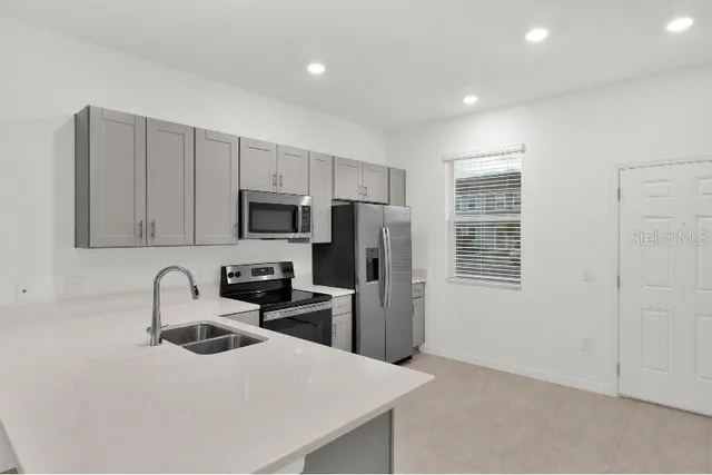 a kitchen with stainless steel appliances a refrigerator sink and microwave