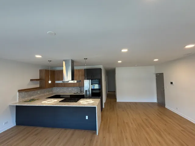 a large kitchen with stainless steel appliances granite countertop a large stove a refrigerator a sink and a microwave oven on the wooden floor