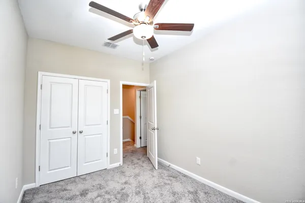 an empty room with closet and a ceiling fan