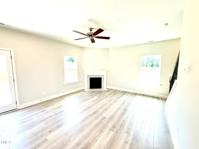 a view of a living room with wooden floor and a ceiling fan