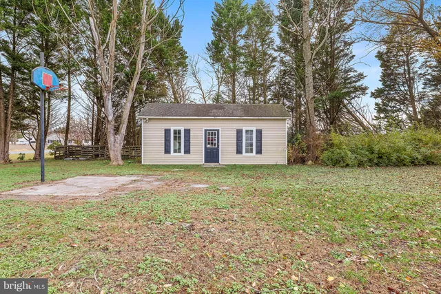 front view of house with a yard and trees all around