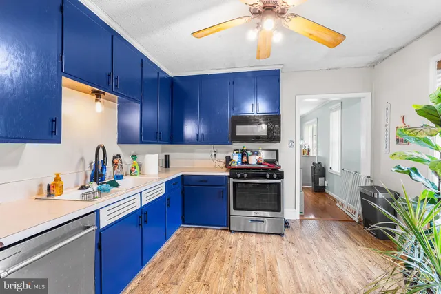 a kitchen with stainless steel appliances kitchen island granite countertop a refrigerator a stove top oven a sink and dishwasher with wooden floor