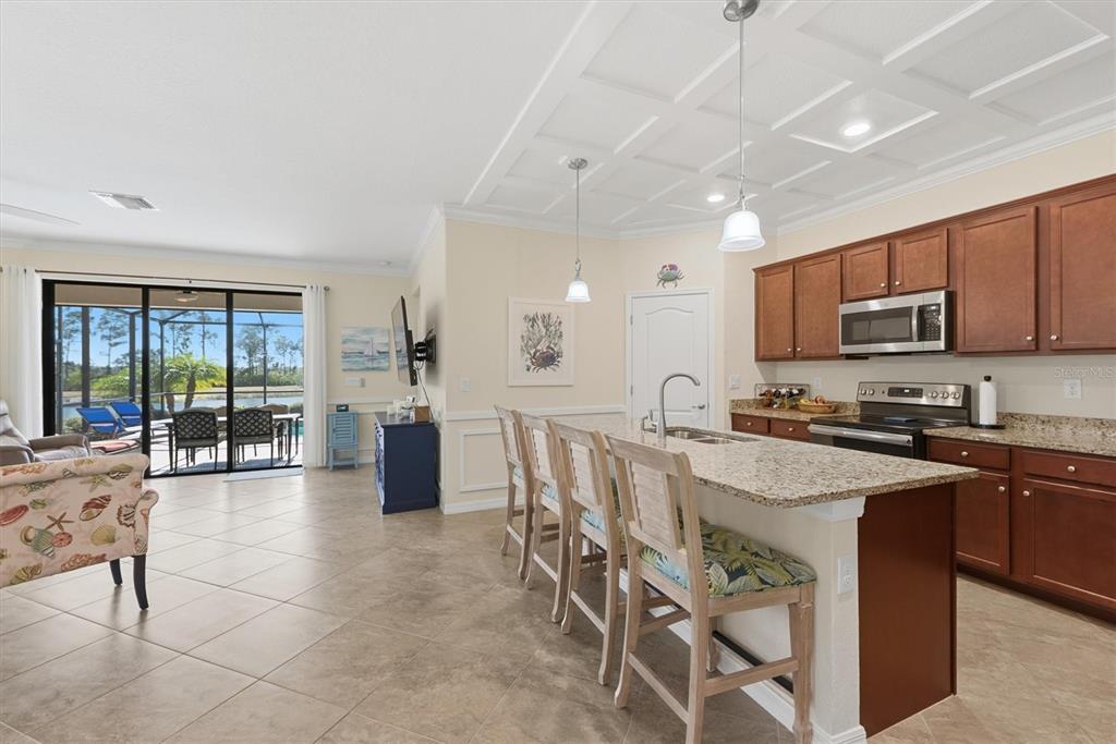10475 Medjool Drive Venice, FL 34293 - Photo 18 of 71 a kitchen with stainless steel appliances granite countertop a stove top oven a sink dishwasher a dining table and chairs with wooden floor