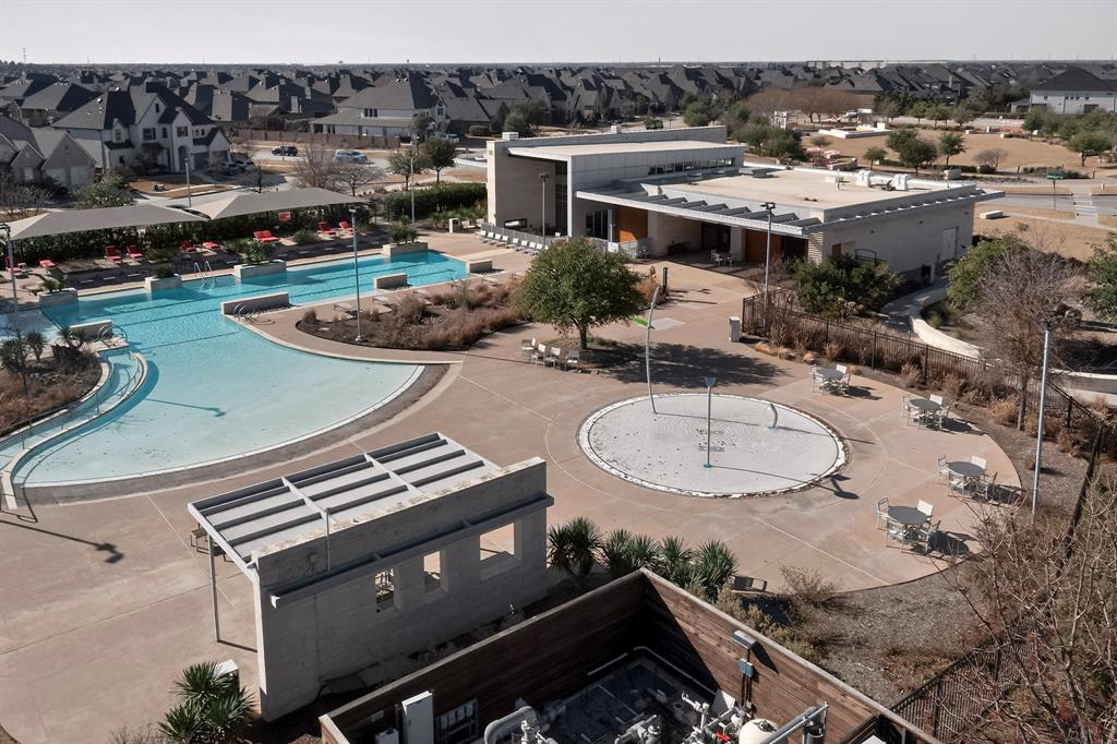 This property offers access to a resort-style amenity center that is conveniently located within walking distance. The world-class HOA facilities include a massive swimming pool with multiple zones, a dedicated splash pad for children, and a modern clubhouse for social gatherings. Surrounded by ample lounge seating and shaded pergolas, this complex serves as a central hub for recreation and relaxation within a high-end residential neighborhood.