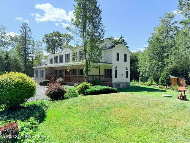 a front view of a house with garden and trees