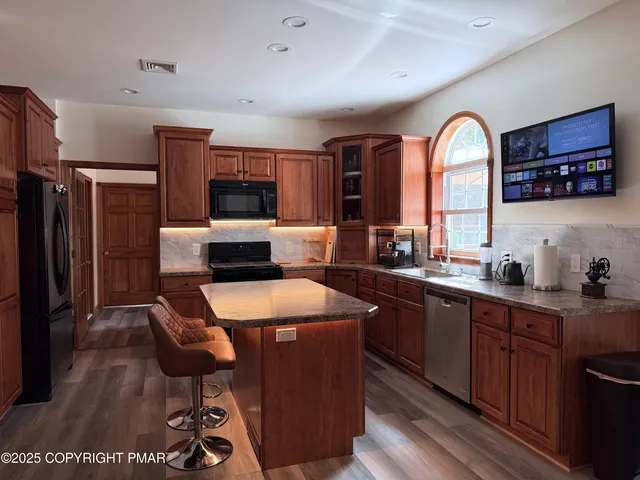 a kitchen with stainless steel appliances granite countertop a stove a sink dishwasher and a refrigerator with wooden floor