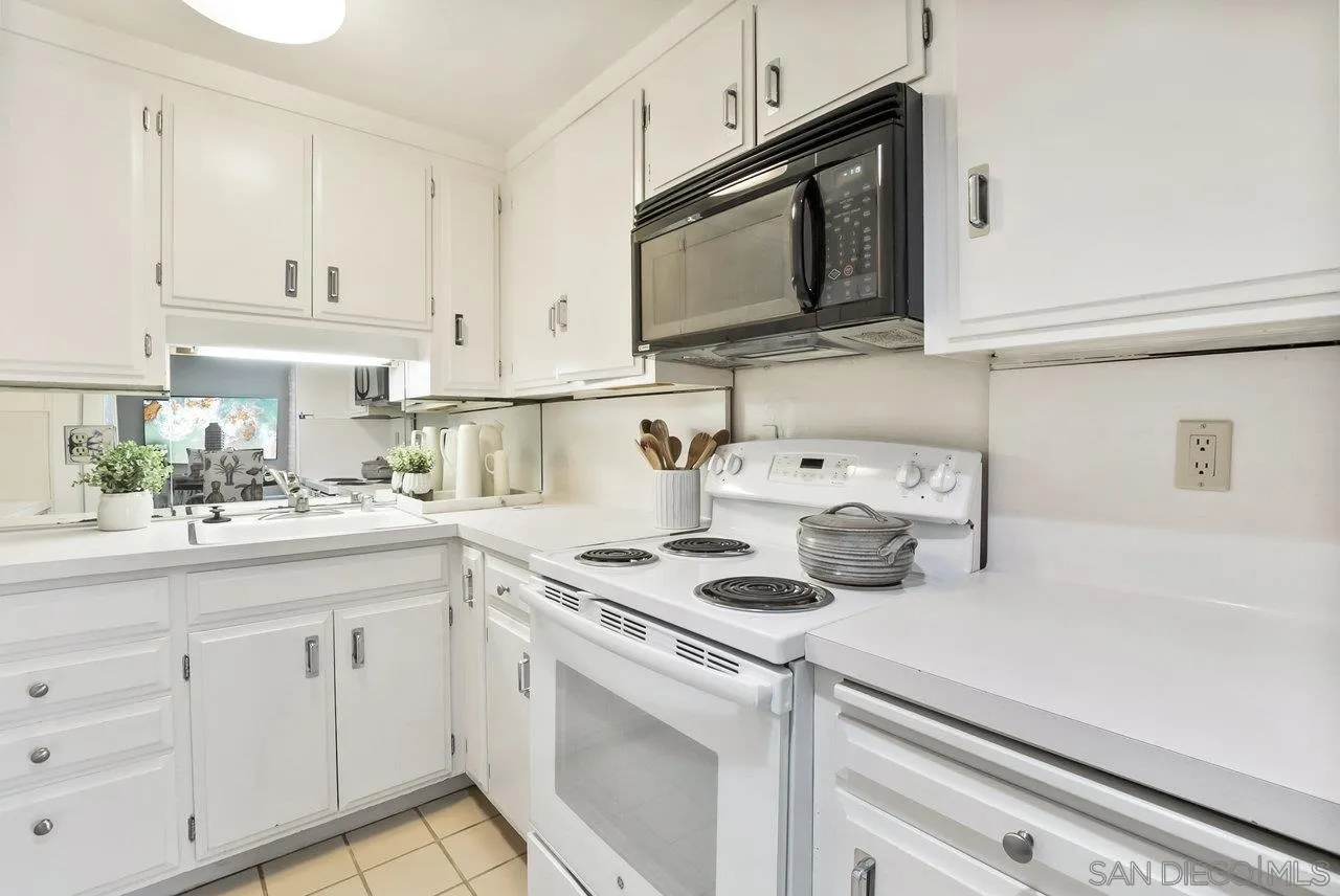 939 Coast Boulevard, Unit 4H La Jolla, CA 92037 - Photo 13 of 39 a kitchen with cabinets stainless steel appliances a sink and a microwave