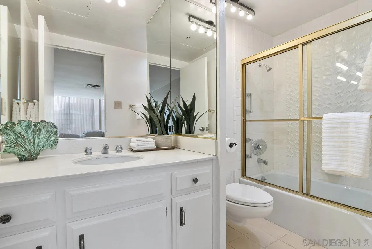 939 Coast Boulevard, Unit 4H La Jolla, CA 92037 - Photo 19 of 39 a bathroom with a granite countertop sink toilet a large mirror a shower and