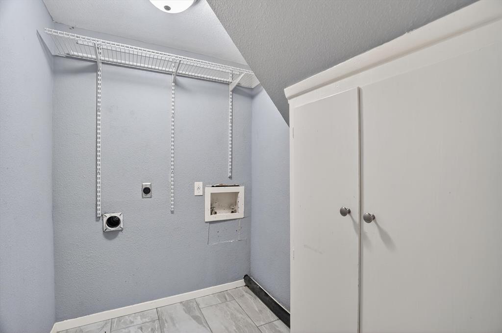 6609 Genoa Road Fort Worth, TX 76116 - Photo 35 of 40 Dedicated laundry area featuring a wire shelving system, built-in white cabinetry with chrome hardware, and wood-finish tile flooring