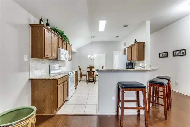 a kitchen with stainless steel appliances granite countertop a table chairs sink and cabinets