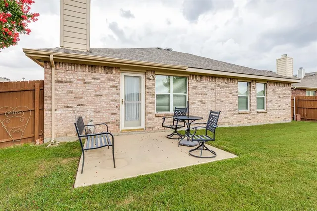 a view of a chair and table in backyard of the house