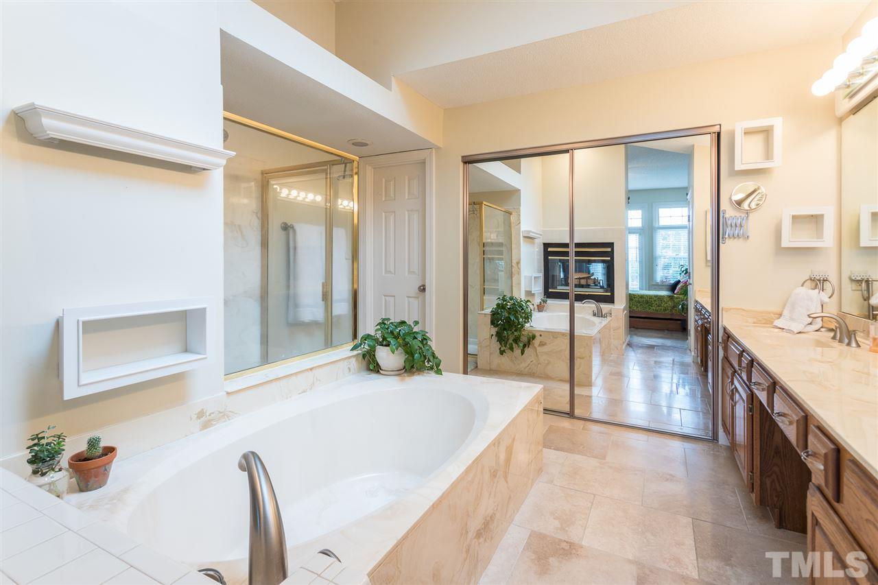 10121 Goodview Court Raleigh, NC 27613 - Photo 23 of 30 a spacious bathroom with a granite countertop tub shower and mirror