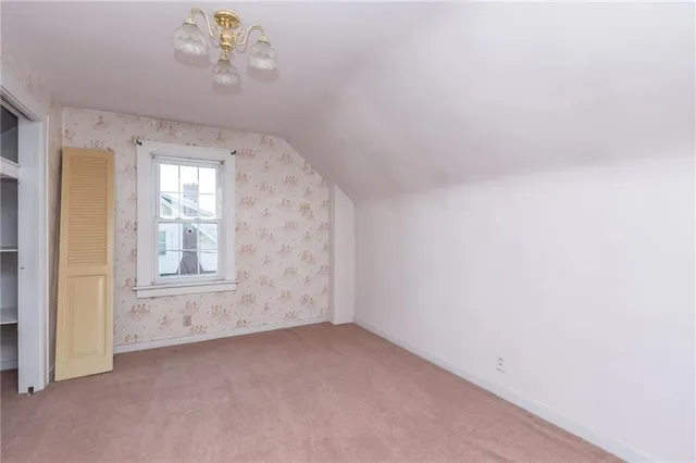 a view of an empty room with wooden floor and fireplace