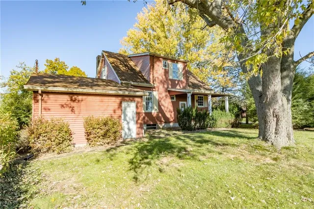 a view of a house with a large tree and a yard