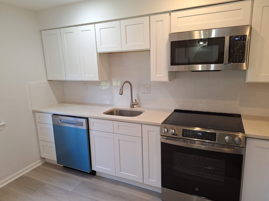 4 Beal's Cove Road, Unit F Hingham, MA 02043 - Photo 16 of 22 a kitchen with stainless steel appliances a stove a microwave and sink