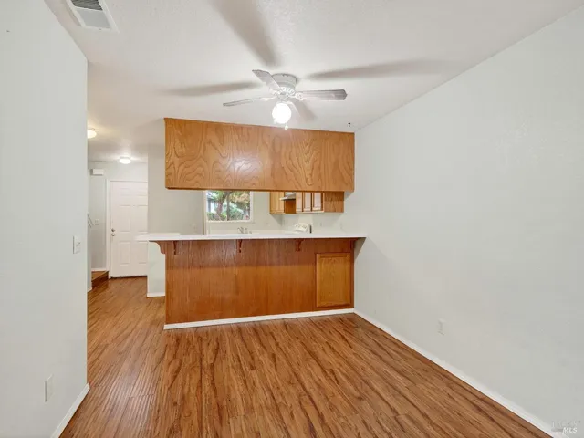 a view of a room with wooden floor and a ceiling fan