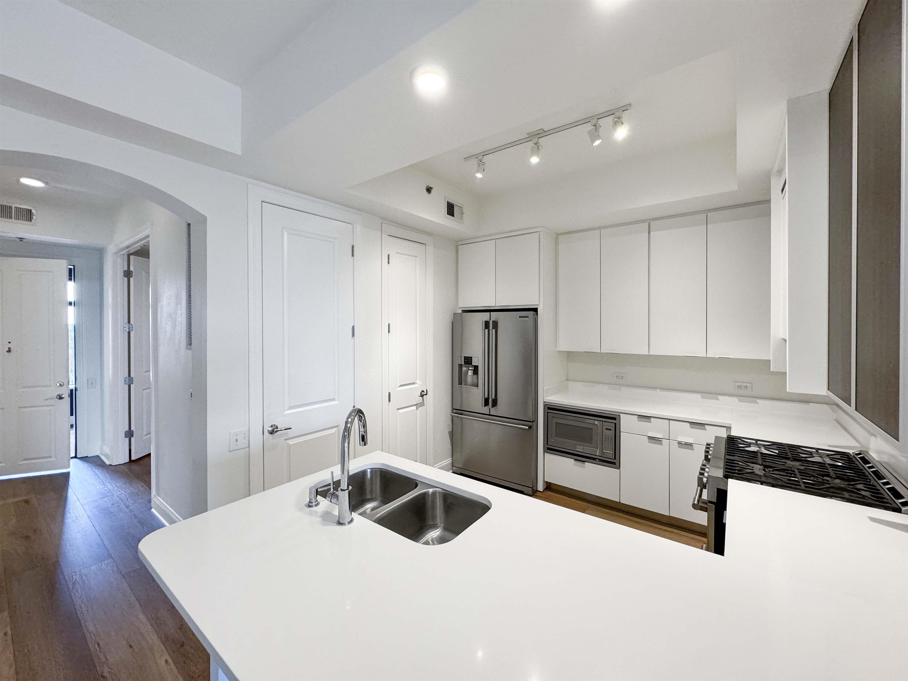 717 Riverside Drive, Unit 707 Memphis, TN 38103 - Photo 12 of 39 Kitchen with dark hardwood / wood-style floors, stainless steel appliances, track lighting, sink, and white cabinets