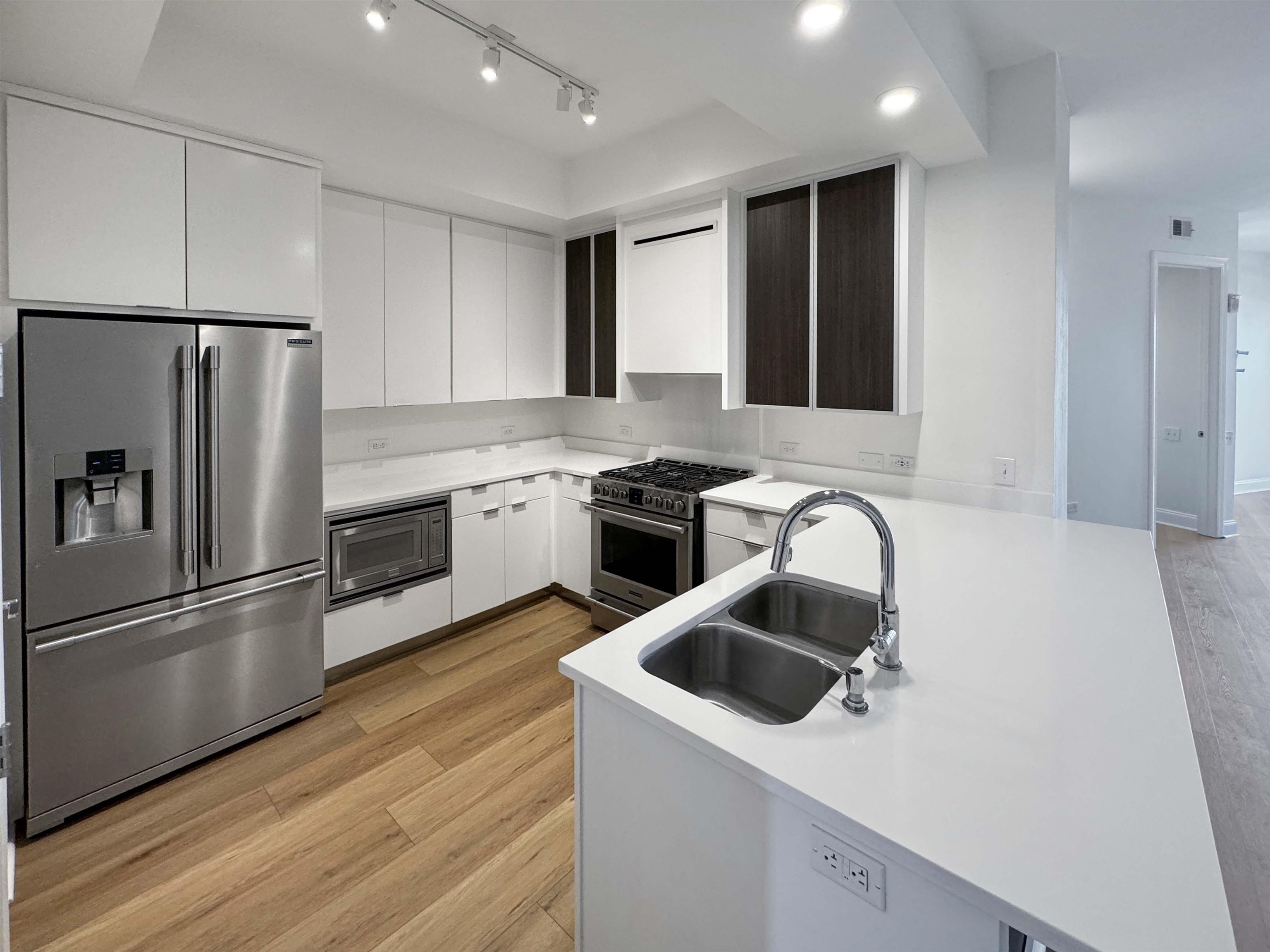 717 Riverside Drive, Unit 707 Memphis, TN 38103 - Photo 13 of 39 Kitchen with light hardwood / wood-style floors, stainless steel appliances, rail lighting, sink, and white cabinets