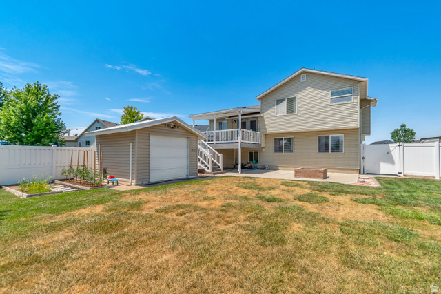4752 South 4075th Street West Roy, UT 84067 - Photo 26 of 28 Expansive backyard featuring a detached storage shed, raised garden beds, a concrete patio, and a built-in fire pit