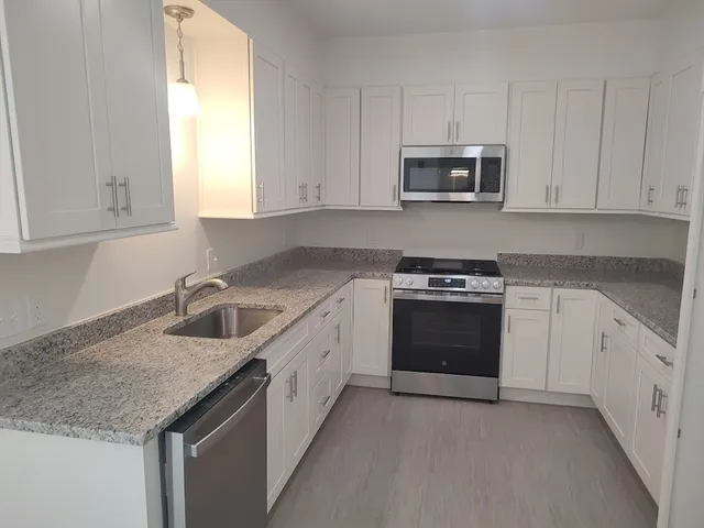 a kitchen with granite countertop white cabinets and stainless steel appliances