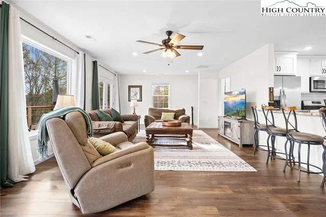 a living room with furniture and a view of dining hall with wooden floor