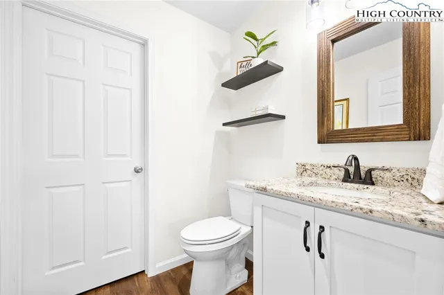 a bathroom with a granite countertop sink vanity mirror and toilet