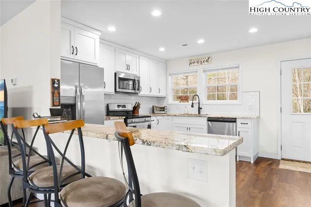 a kitchen with stainless steel appliances kitchen island granite countertop a refrigerator a stove a microwave oven with a dining table and chairs