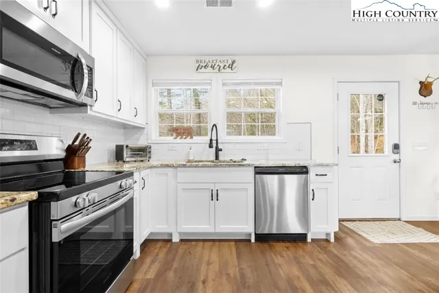 a kitchen with stainless steel appliances granite countertop a stove a sink and a microwave