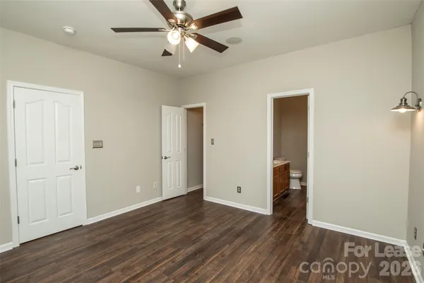 an empty room with wooden floor and ceiling fan