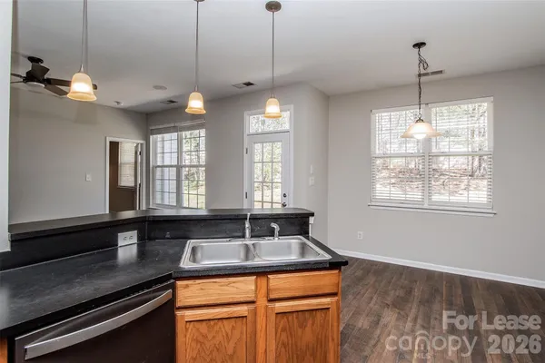a kitchen with stainless steel appliances granite countertop a sink a window and chairs
