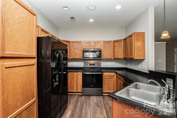 a kitchen with granite countertop a refrigerator sink and stove