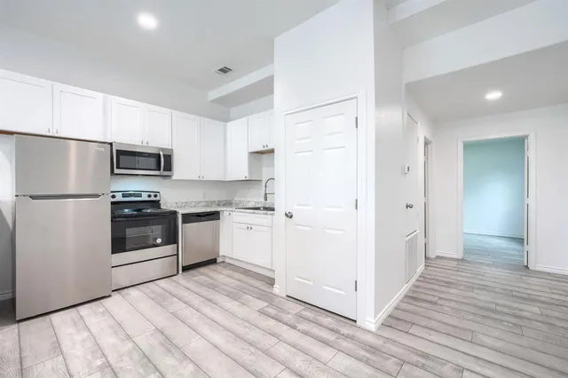 a kitchen with granite countertop a refrigerator and a stove top oven