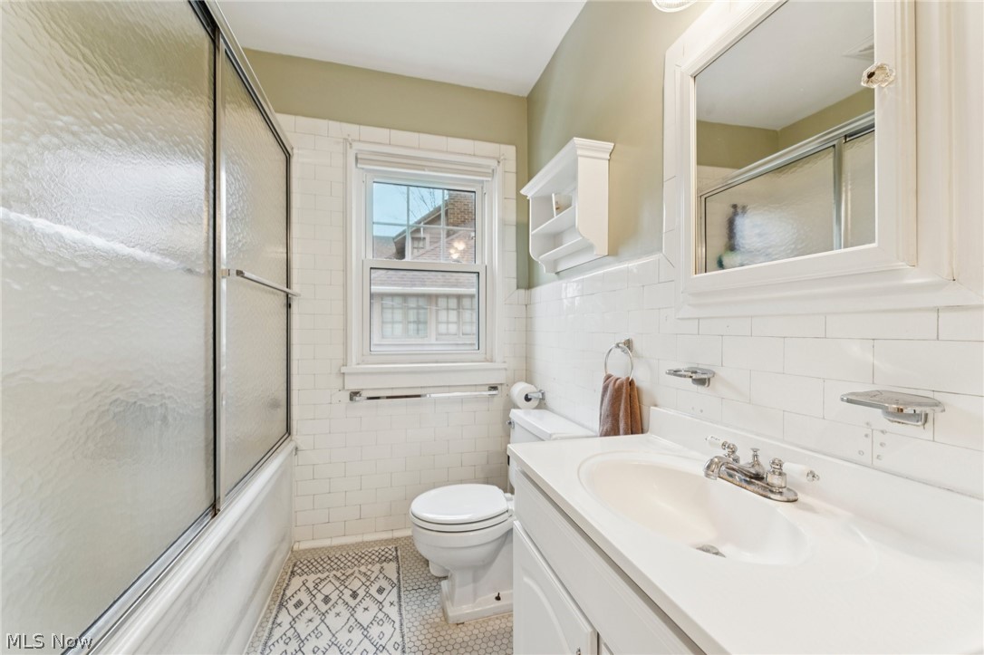 2925 East Overlook Road Cleveland Heights, OH 44118 - Photo 27 of 48 The bathroom features a vanity with an integrated sink, a mirror with a white frame, and a shower with frosted glass doors