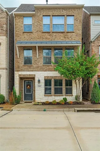 front view of a brick house with a potted plant and a large window
