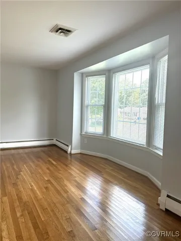 a view of an empty room with wooden floor and a window