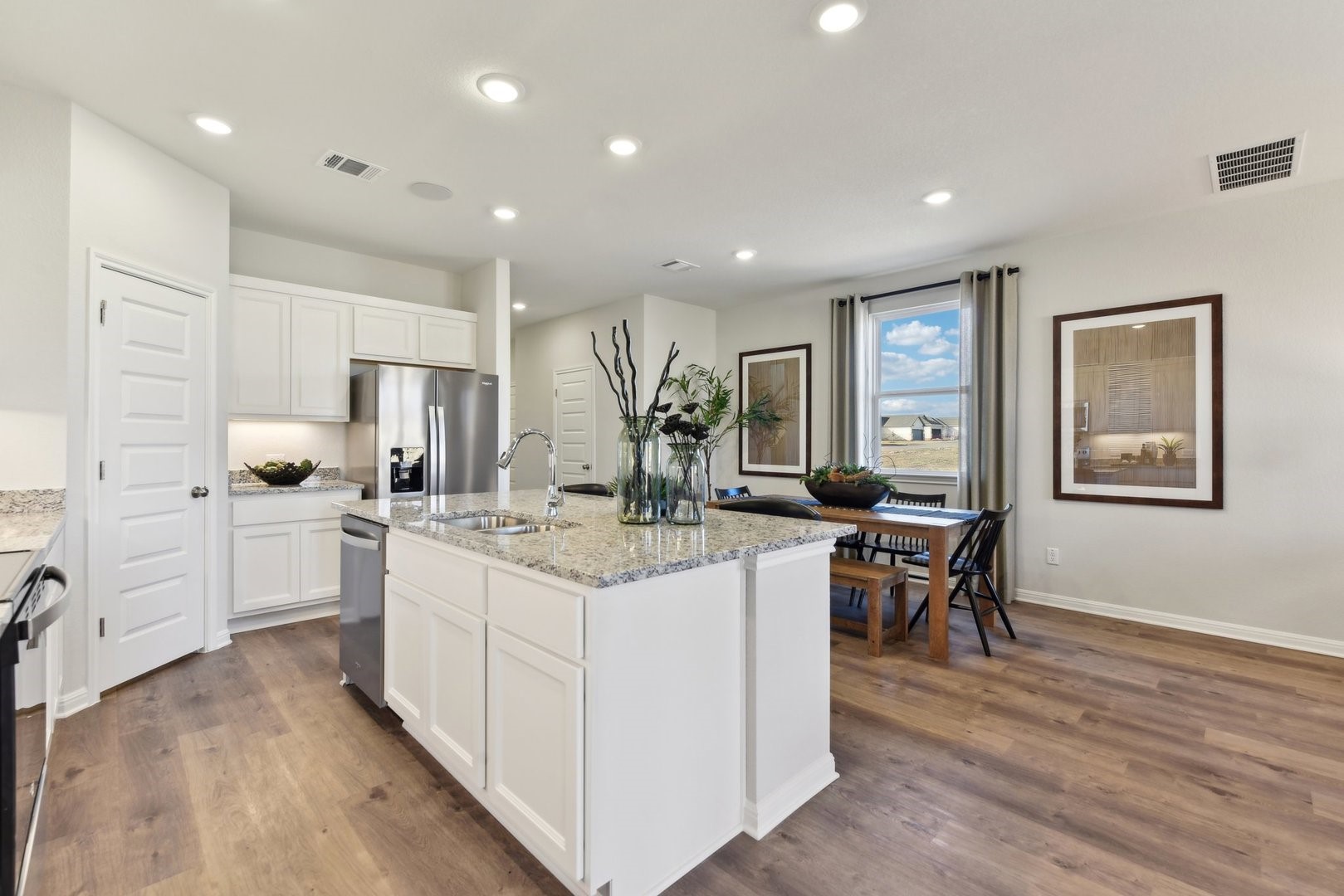 208 Firefox Way Jarrell, TX 76537 - Photo 5 of 17 Granite counters and stainless steel appliances outfit this open-concept kitchen with recessed lighting and warm wood flooring.