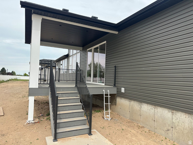 3839 West 825 North, Unit WF18 West Point, UT 84015 - Photo 21 of 22 Rear exterior featuring a covered deck with white columns, dark gray composite decking, and black metal railings