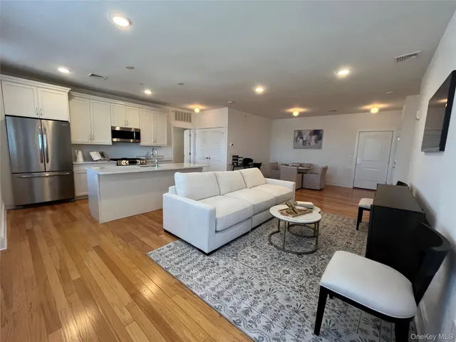 a living room with stainless steel appliances furniture and a wooden floor
