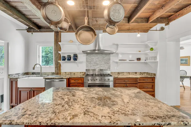 a kitchen with stainless steel appliances granite countertop a stove top oven a sink dishwasher a dining table and chairs with wooden floor