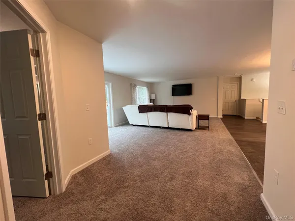 a living room with furniture and a walk in closet with wooden floor