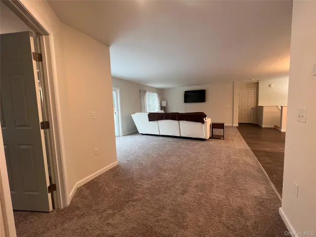 a living room with furniture and a walk in closet with wooden floor